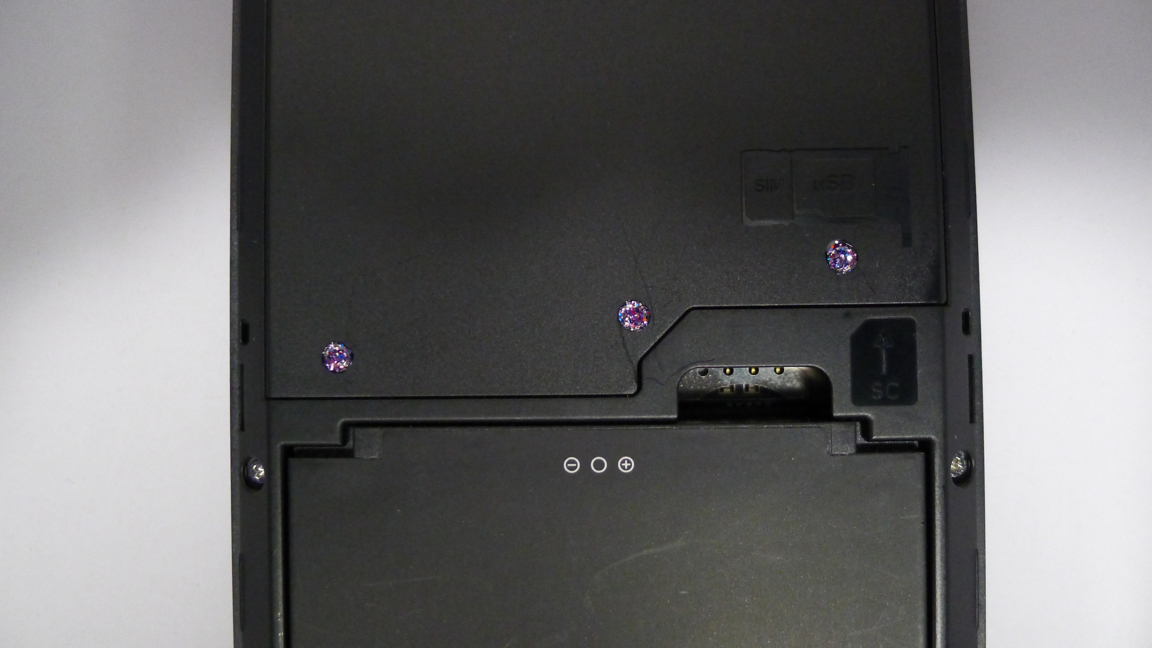 A close up of Librem 5 USA with anti-interdiction purple glitter nail polish covering the modem and WiFi screws